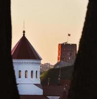 View on Gediminas Tower in Vilnius between two tree trunks framing the view in sunset sky photo
