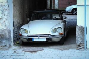 White Citroen vintage car parked in old town arch of a brick building photo