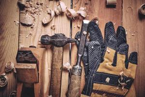Carpenters tool kit, hammer, chisel and plane with gloves wooden background. photo