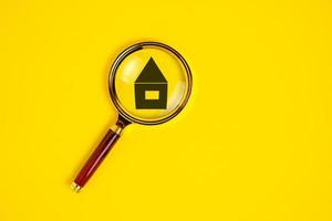 Icon house under the magnifying glass. Concept of finding, buying and renting real estate. photo