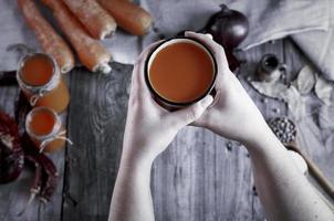 Iron mug with carrot juice in female hands photo