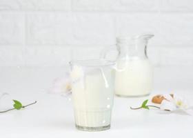 full glass cup of fresh milk with splashes stands on a white table, healthy breakfast photo