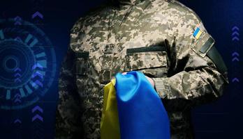 soldier of the Ukrainian armed forces stands with a blue-yellow flag of Ukraine on a black background. Honoring veterans and commemorating those killed in the war photo