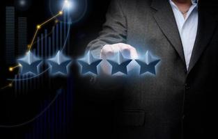 five holographic stars and a man's hand on a dark blue background. Business evaluation concept by users, rating and voting photo