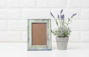 empty white wooden photo frame and flowerpots with plants on white table