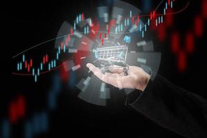 man's hand holds a miniature shopping cart on a dark blue background, the concept of the start of world sales, the growth of purchases. Online shopping photo