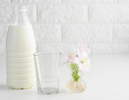 plastic bottle with milk and empty glass cup on a white table. Breakfast photo