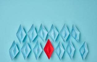 group of paper boats on a blue background. concept of a strong leader in a team, manipulation of the masses, following new perspectives, collaboration and unification. Startup photo