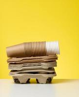 stack of paper disposable brown cups and holder on white table, yellow background photo