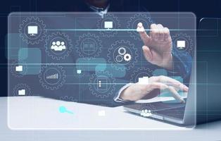 a woman sits at a table and works on a laptop and a virtual hologram with analytical icons in business. Process analysis concept, efficient management photo