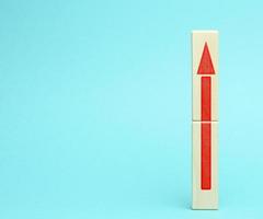 wooden block with an upward arrow on a bluee background, the process of growth and achievement of goals photo