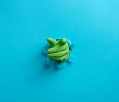 hand in a yellow latex glove points a finger on a blue background photo