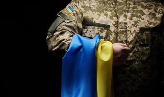 Ukrainian soldier holds a flag of the independent state of Ukraine. Steadfastness and courage of the people in the fight against the invaders. Unbroken spirit of the nation. Symbol of independence photo