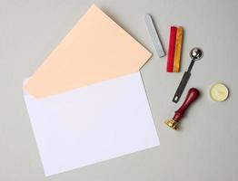 white envelope and items for sealing with wax seal on gray background photo