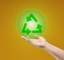 female hand holds recycling icon on yellow background. Responsible attitude to nature resources photo