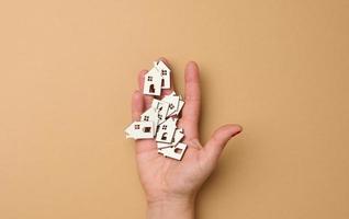 Woman's hand holds miniature wooden houses. Real estate search concept for rent, mortgage, real estate insurance photo