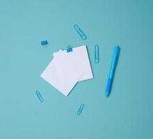 stack of white square sheets of paper for notes, stationery on blue background, top view photo