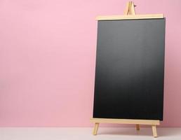 empty black slate board on white table, pink background. Place for the inscription of the announcement photo