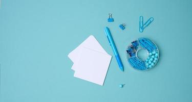 stack of white square sheets of paper for notes, stationery on blue background, top view photo