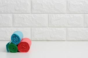 stack of disposable plastic trash can bags on white table, white brick wall background photo