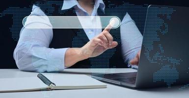 a woman sits at a table and works on a laptop. The concept of searching for information on the Internet, remote work, networking communication photo