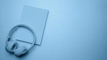 blue wireless headphones and a closed notepad on a blue background. photo