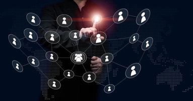 a man in a black suit stands in front of a virtual screen with icons of people. The concept of holding an online meeting, the selection of international staff photo