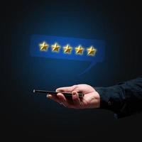 a man's hand holds a smartphone and five gold stars above it. App evaluation. User reviews photo