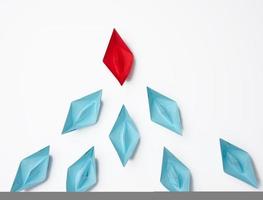 group of paper boats on a white background. concept of a strong leader in a team, manipulation of the masses, following new perspectives, collaboration and unification photo