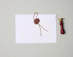 sealed white envelope with brown wax seal on gray background, flat lay photo