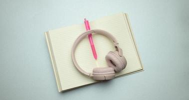beige wireless headphones and a open notepad on a gray background photo