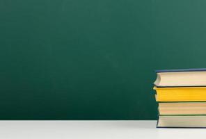 stack of books on blank green school board background photo