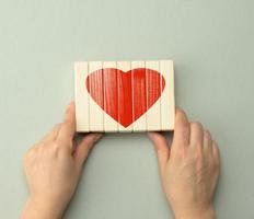 collected red heart on wooden bars held by two hands. Concept of love, friendship photo