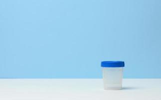 empty plastic container for the collection of analyzes on a white table, blue background photo