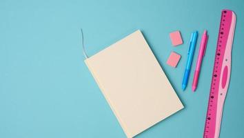 notebook and pink ruler on blue background, top view photo