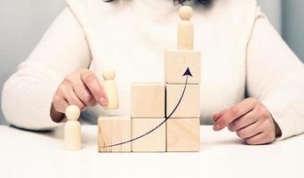 pyramids from wooden cubes and figurines of men on the table. The concept of achieving goals, moving up the career ladder. Detection of single-minded personality photo