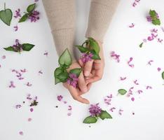 two hands of a young girl with smooth skin and a bouquet of pink flower photo