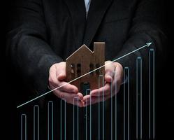 Hand holds a wooden model of a house on a dark background. Real estate sale and purchase concept photo