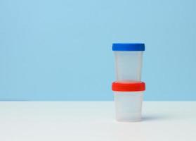 empty plastic container for the collection of analyzes on a white table, blue background photo