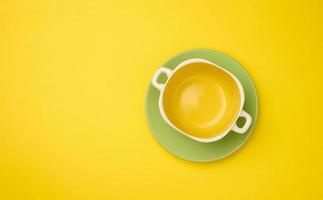 empty yellow soup plate on a yellow bacground, top view photo