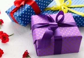 boxes packed in festive purple paper and tied with silk ribbon on white background, birthday gift, surprise photo