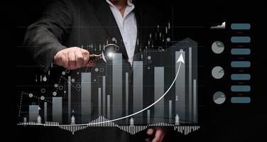 man in a black shirt stands in front of a holographic graph with growing indicators. Business growth, sales increase. High performance photo