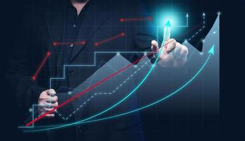 man in a black shirt stands in front of a holographic graph with growing indicators. Business growth, sales increase. High performance photo