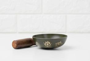 Tibetan singing copper bowl with a wooden clapper on a white wooden table, objects for meditation and alternative medicine photo