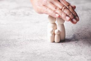 Hands holding wooden dolls with copy space. Family protection and insurance coverage concept. photo