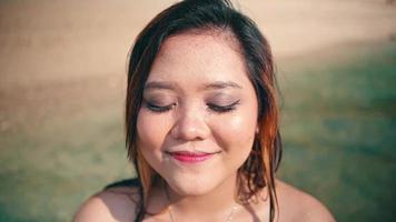 an Asian woman with blonde hair and red lips is enjoying the beauty of an island by playing in the water on the beach video