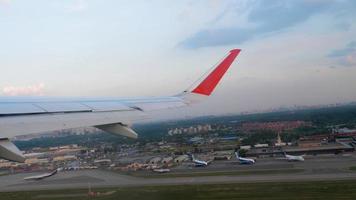 Airplane takeoff over Moscow, climb. View from the porthole city and airport. Aircraft wing, POV view video