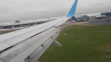 View from the porthole on the wing, landing at an unrecognizable airport. Tourism and travel concept video