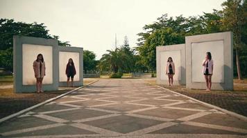 een groep van Aziatisch Dames staand in voorkant van een muur afzonderlijk met heel eng uitdrukkingen in een park video