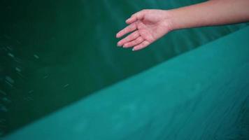 A woman's hand plays with the blue sea water from a boat while sailing a fishing boat across the ocean video